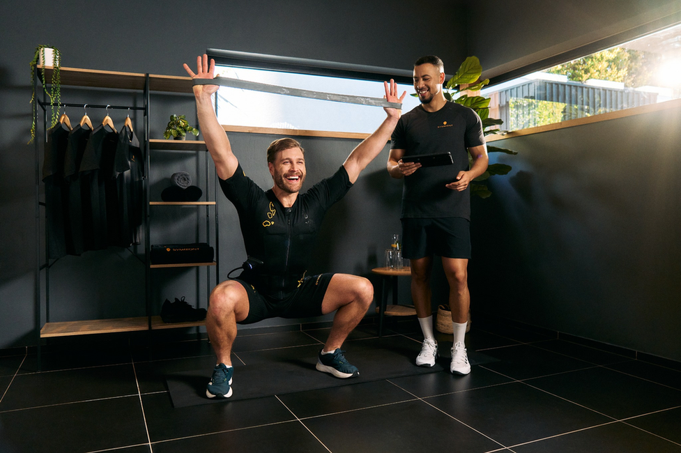 Professional EMS Coaching and Training – Tailored Guidance for Optimal Fitness Results Man training with a personal trainer in a SYMBIONT EMS studio, showcasing positive energy, motivation, and personalized training and coaching.
